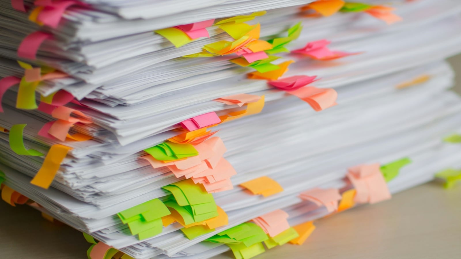 A stack of paper records marked with coloured sticky tabs